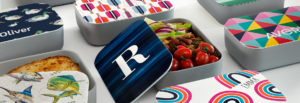 A collection of lunch boxes featuring diverse designs, showcasing vibrant colors and unique patterns.