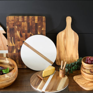 A wooden cutting board showcasing a bowl, charcuterie, and an assortment of kitchen items neatly arranged for food preparation.