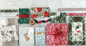 A collection of colorful Christmas wrapping paper and various gift-wrapping supplies arranged neatly on a festive background.