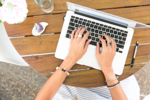 A woman engaged in typing on her laptop at a table, showcasing concentration in a comfortable workspace.