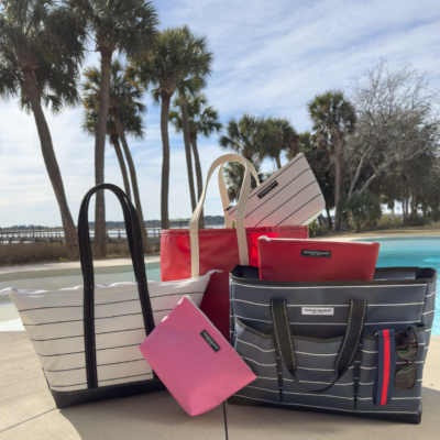 bags displayed by a swimming pool, featuring different designs and colors, with water glistening nearby.
