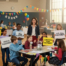 A group of children gathers around a table, holding colorful signs promoting their school fundraising efforts. Charleston Wrap, School Fundraising, Tote Bag Fundraising, Gift Wrap Fundraising